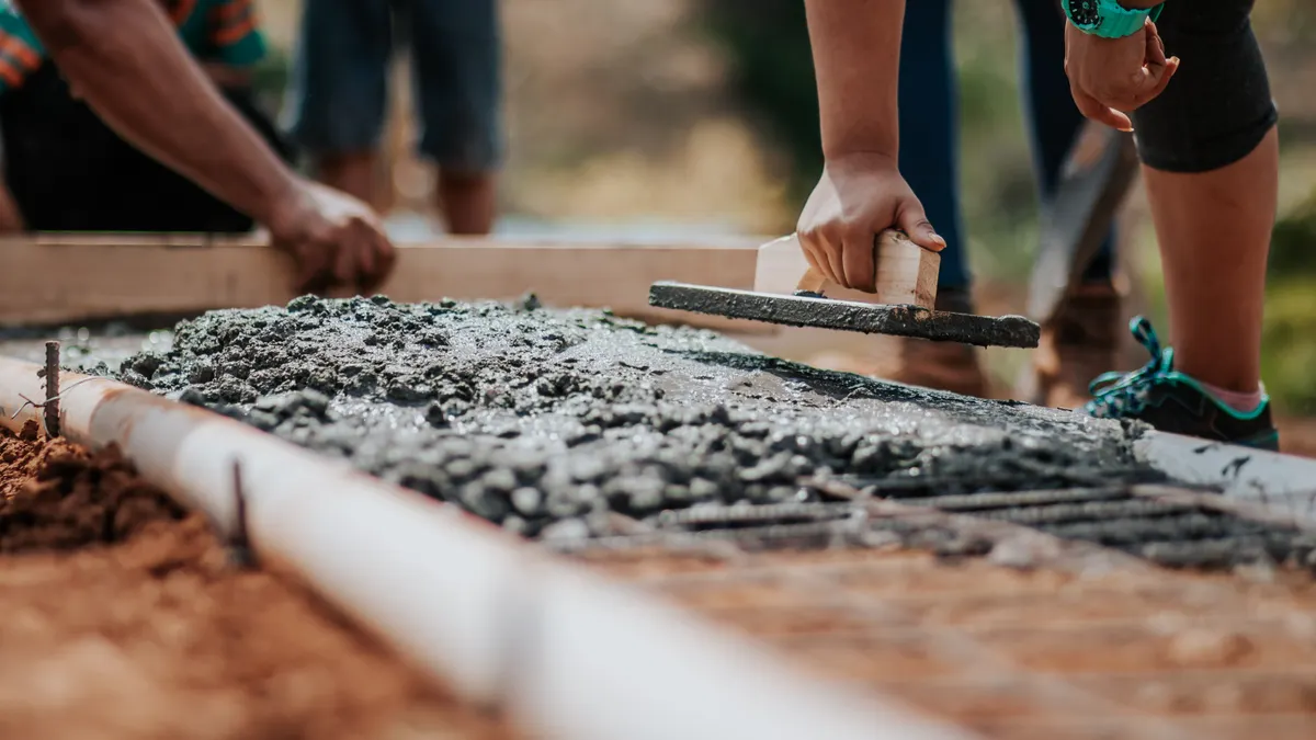 Workers pouring and smoothing wet concrete for a slab foundation