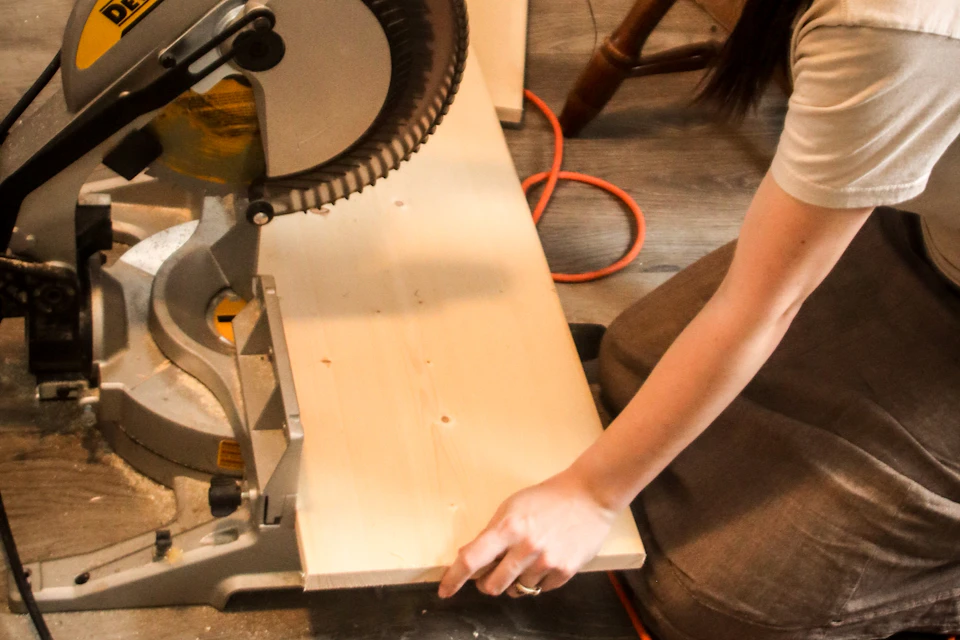 DIYer holding a board against a miter saw for a crosscut