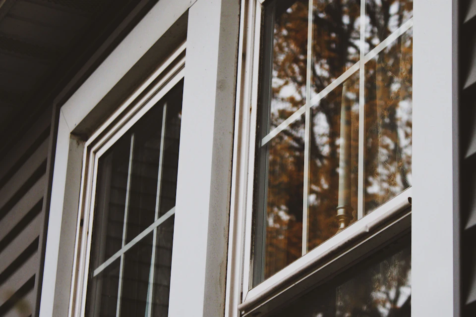 Close-up of white double-hung windows with grid panes on a house exterior