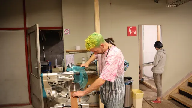 Woodworker cutting lumber on a compound miter saw in a workshop